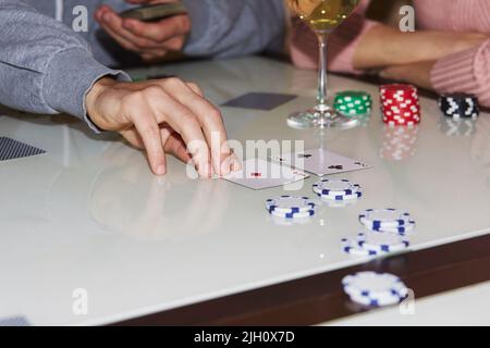 Laying out cards on the table in poker game. Players with dices and cards. Glass of champagne. Gambling concept. Candid moment. Poker background photography. Selective focus. Stock Photo