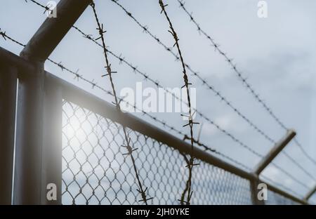 Prison security fence. Border fence. Barbed wire security fence. Razor wire jail fence. Boundary security wall. Prison for arrest of criminals Stock Photo