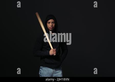 African american hooligan holding baseball bat isolated on black Stock Photo