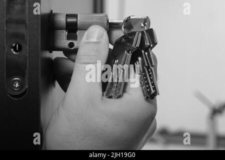 The master installs the core for the door lock, installation work with the door. Stock Photo
