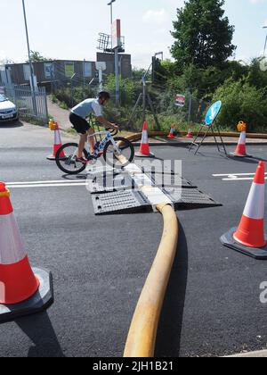 Iwade, Kent, UK. 14th July, 2022. Problems remain with Isle of Sheppey's water supply. Some residents are still without water nearly 3 days after the main water pipe supplying the island burst - although many in Sheerness & Minster were reconnected late last night. A long (reported to be 5km) fire hose is being used to pump water near the Sheppey Crossing to help resolve the problem (according to Kent Online) - but even this sprung a leak with water seen shooting high into the air (repaired by the time of these pics). Credit: James Bell/Alamy Live News Stock Photo