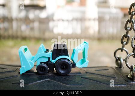 Tiny plastic tiny tractor toy with shovels close up still Stock Photo