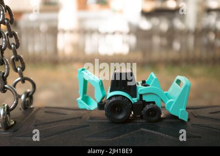 Tiny plastic tiny tractor toy with shovels close up still Stock Photo