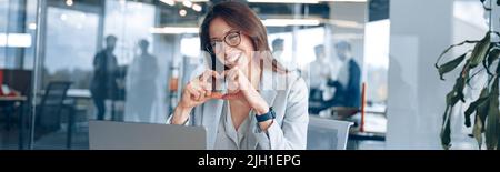 Happy businesswoman communicating in video call with friends during lunch break at modern office Stock Photo