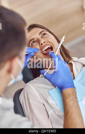 Professional male doctor is doing anestetic injection to happy female patient in stamotology cabinet Stock Photo