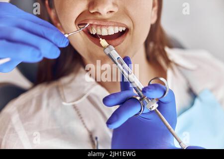 Professional male doctor is doing anestetic injection to happy female patient in stamotology cabinet Stock Photo