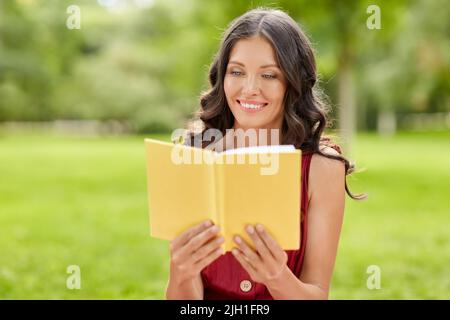 happy smiling woman reading book at park Stock Photo