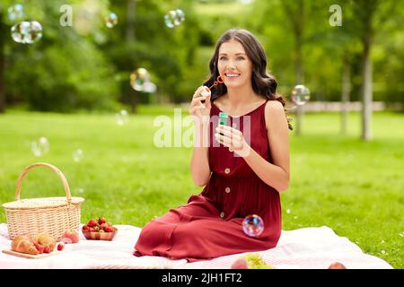 happy woman blowing soap bubbles at picnic Stock Photo