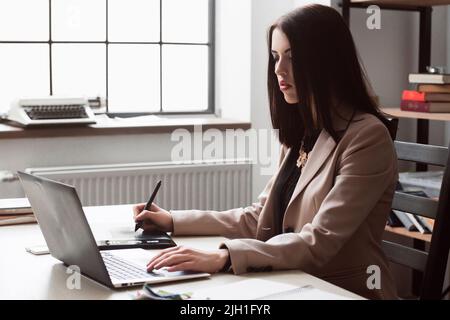 Female designer editing artwork using graphics tablet and stylus. Creative retoucher working on new project in office. Stock Photo
