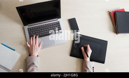 Top view on designer working on laptop with black screen and graphic tablet, workplace of successful creative programmer Stock Photo