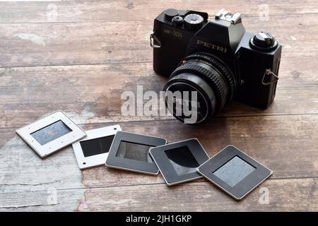 Vintage Petri camera with slides on wooden background. Retro style technology Stock Photo