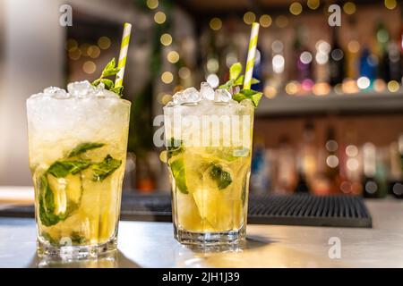 Mojito cocktail on bar counter with lemons, limes and species with copy space for text. Stock Photo