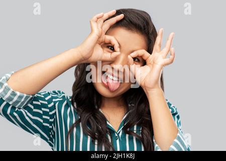 smiling asian woman looking through finger glasses Stock Photo
