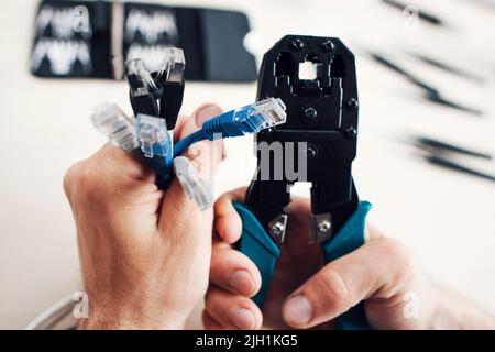Hands holding cables and forceps for crimping plug Stock Photo
