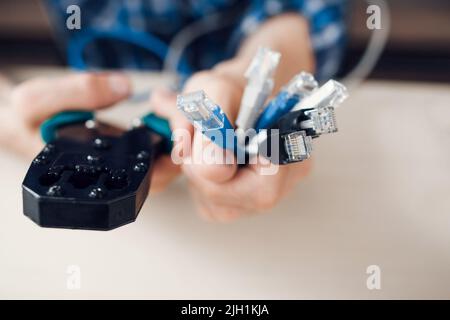 Hands holding cables and forceps for crimping plug Stock Photo