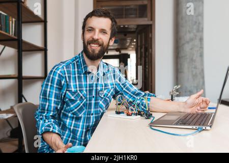 Happy programmer smiling at camera near laptop Stock Photo