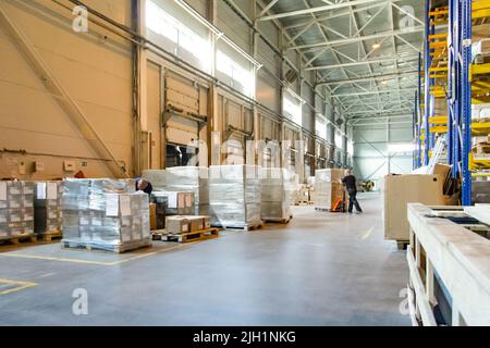 Worker near forklift truck with cardboard boxes in warehouse. Logistics ...