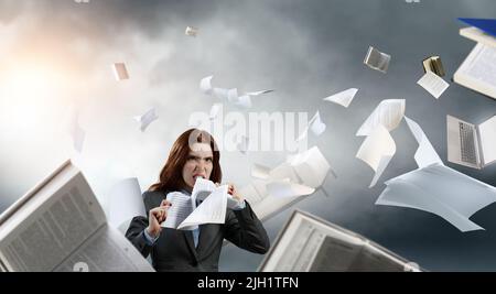 Young stressed woman ripping documents with frustrated facial expression. Stock Photo