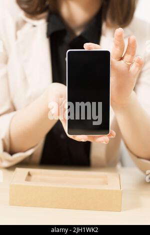 Unrecognizable woman shows new model of smartphone Stock Photo