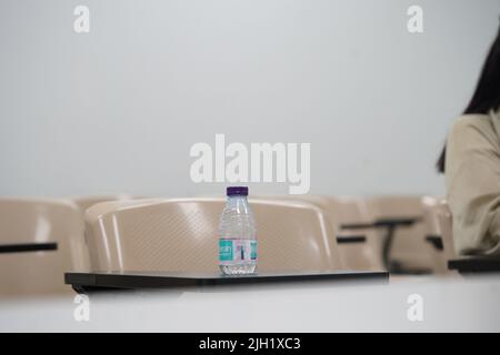 Empty class at university or school with chairs and side table, also a water bottle and the chairs are arranged in rows. Stock Photo