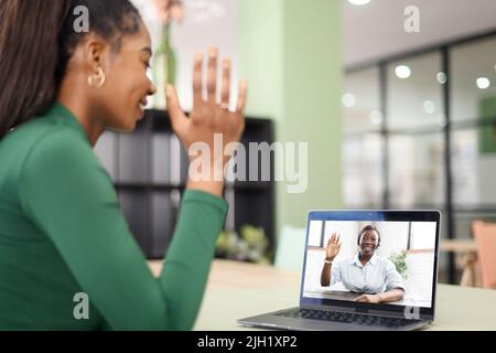Female freelancer, student, colleague using laptop for virtual meeting with teacher or manager, taking educational course, talking online with confident woman. Two women involved video call, waving Stock Photo