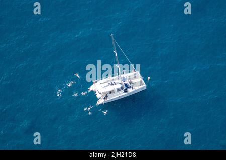Boat and people swimming in the highest sea cliff in Europe at 1,903 feet (580 meters) above the sea. Cabo Girão bay, Madeira Island, Portugal. Stock Photo