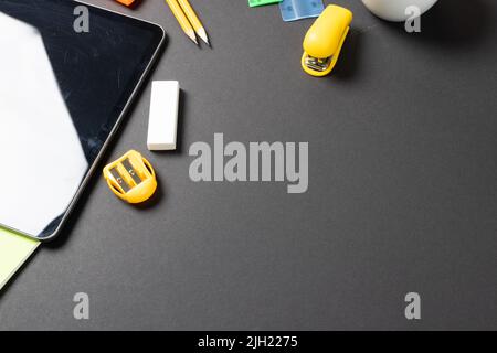 Imagine of various office supplies, pins, rulers, scissorson and tablet on black background Stock Photo