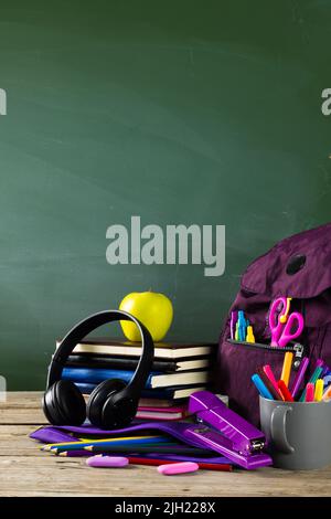Image of various school supplies on wooden table over black board Stock Photo