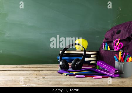 Image of various school supplies on wooden table over black board Stock Photo