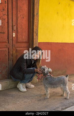 Latin woman petting her schnauzer dog in an old town in Mexico Stock Photo