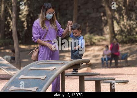 Baby boy climbing steps at the park holding his mother's hand Stock Photo