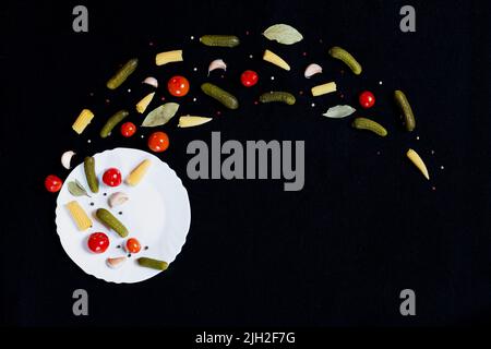Small canned vegetables fly from a plate on a black background Stock Photo