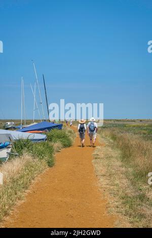 Couple walking summer, rear view of a mature couple walking the North Norfolk Coast Path on a hot summer day near Blakeney, Norfolk, England, UK Stock Photo