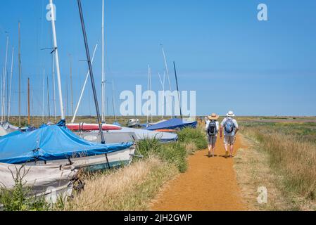 Couple walking summer, rear view of a mature couple walking the North Norfolk Coast Path on a hot summer day near Blakeney, Norfolk, England, UK Stock Photo