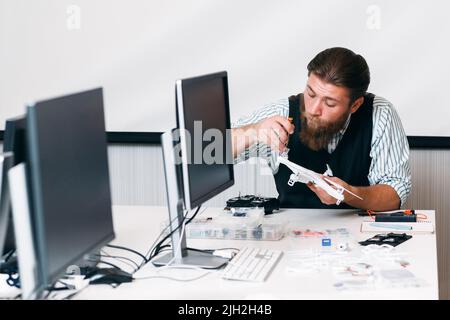 Bearded master disassembling drone in office Stock Photo