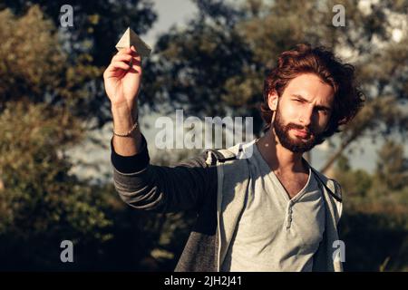 Young pleased guy playing with paper airplane Stock Photo