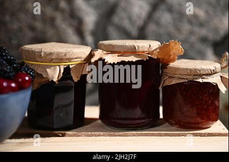 Collection of homemade jam from red currant, cherries and blackcurrant on a wooden surface. Canned food, canning concept Stock Photo