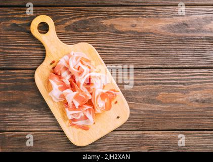 Pieces of smoked pork bacon meat food on a cutting board on wooden background, mockup. Copy space Stock Photo