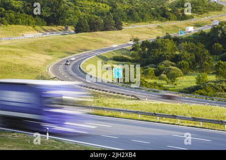 Highway with traffic in daylight. Fast blurred motion drive on the highway at beautiful sunny day.  Transportation and travel concept Stock Photo