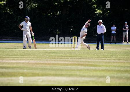 Fast bowler approaches the stumps to bowl at the batsman in a summer league cricket match in Huddersfield, Yorkshire, England Stock Photo