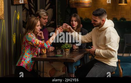Two amazing and attractive couples are drinking and having fun in the bar Stock Photo