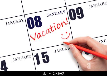 8th day of January. A hand writing a VACATION text and drawing a smiling face on a calendar date 8 January. Vacation planning concept. Winter month, d Stock Photo