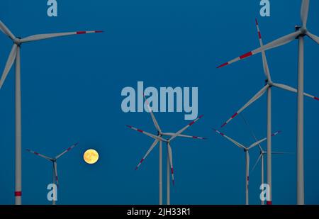 Sieversdorf, Germany. 12th July, 2022. The moon, which is about 95 percent visible and waxing, glows yellowish in the sky between wind turbines shortly after sunset. On the night of July 13, 2022, a super full moon can be seen in the sky if visibility is good. At moonrise around 10 p.m., the Earth's satellite will be 357,517 kilometers from Earth. Despite this distance, it will be the largest supermoon of the year. Credit: Patrick Pleul/dpa/Ģ����ý Live News Stock Photo