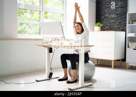 Close-up Of A Happy Businesswoman Relaxing On Fitness Ball In Office Stock Photo