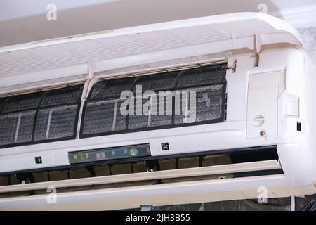 The man takes out filters from the air conditioner for cleaning. Split system maintenance. Stock Photo