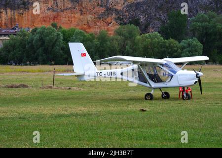 White single-engine airplane on grass in nature Stock Photo