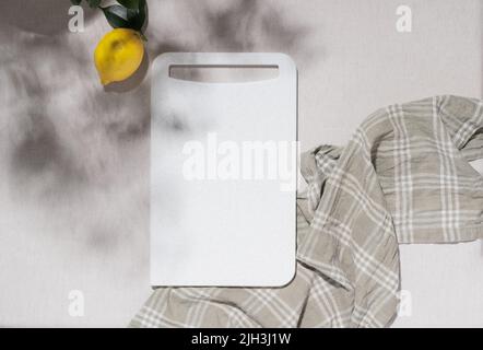 Empty white cutting board ripe lemon lie on the kitchen table, top view flat lay, mockup Stock Photo