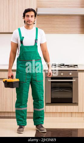 Young contractor repairing oven in kitchen Stock Photo