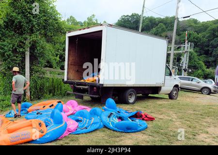 Effort, hard work, the insurmountable weight of a difficult task ahead; man with the job of inflating large quantity of vinyl tubes for river tubing. Stock Photo