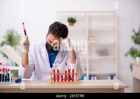 Young biochemist testing blood samples in pandemic concept Stock Photo